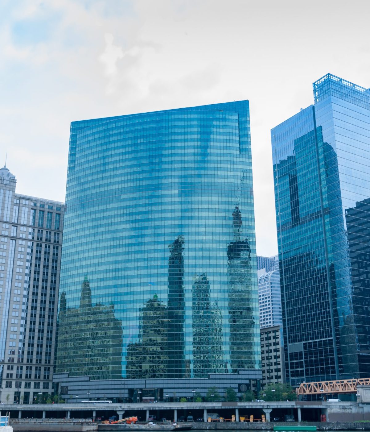Chicago commercial high-rise skyline rising above river. Chicago commercial high-rise skyline rising above river with glass curtain exteriors reflecting buildings on otherside.